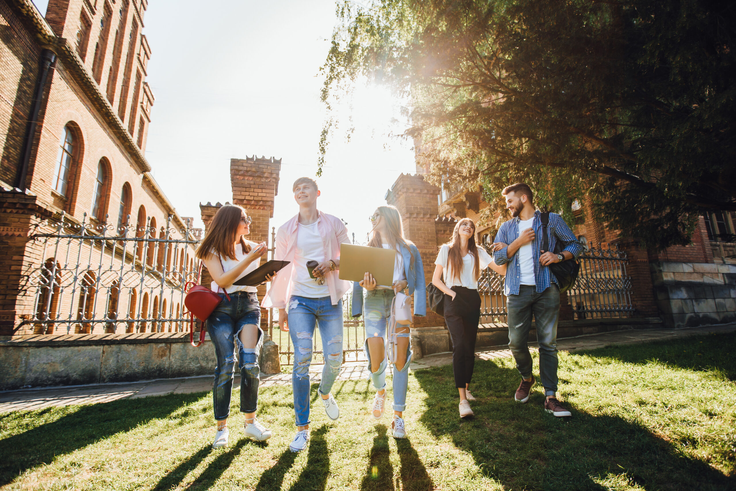 group of friends walking on campus with computers