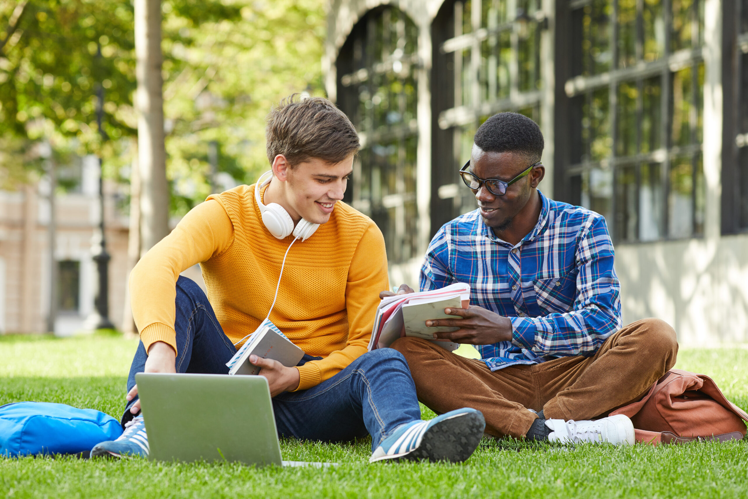 two student studying in grass on campus
